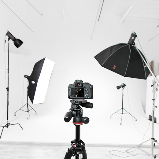 Intérieur d'un studio photo, équipé d'un trépied et de deux parapluies pour l'éclairage.